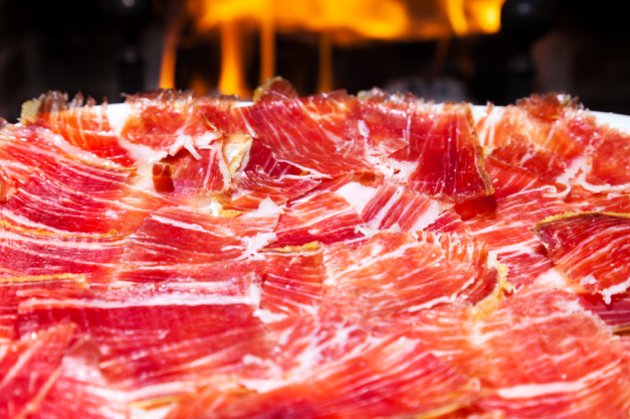 plate of Spanish jamon iberico slices (serrano ham) with a fireplace as background
